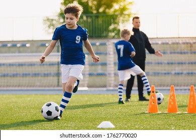 10 Year Old Boy Running Soccer Ball. Elementary Age School Kids On Football Training With Young Coach. Children Sports Team Improving Dribbling Speed And Agility Skills On Session With Training Cones