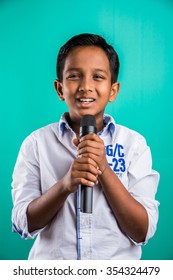 10 Year Old Cute Indian Kid /boy In White Shirt Yelling Or Singing In Microphone, Isolated Over Green Background