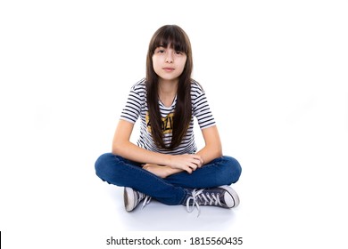 10 year old girl sitting with crossed legs on floor while crossing arms and look serious and straight into camera 