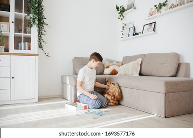 10 Years Boy Playing Puzzles At Home. Child Connecting Jigsaw Puzzle Pieces Sitting At Floor In A Living Room. Playing With Dog. Fun Family Leisure. Stay At Home Activity For Kids.