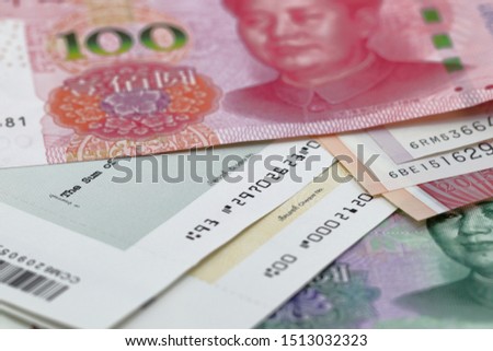 100 China yuan stack over Singapore dollar bill, and part of cheque, banknote, finance trade business, forex, wealth, pile of cash, paper money, financial with selective focus landscape format