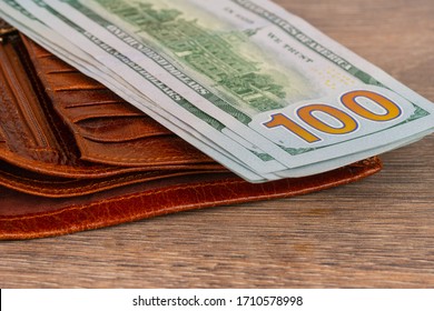 100 Dollars Banknotes With Orange Wallet On Wooden Table. Pension Or Unemployment Benefit Concept.