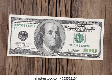 100 dollars on old wooden table  - Shutterstock ID 753552184