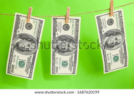 100 dollars on a rope, dollars with a clothespin on a rope isolated on a green background, Concept - money laundering. Dollars are dried on the ropes. Dollars after washing. Money earned honestly