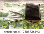 100 euros in a black leather wallet lie on banknotes. Lots of money