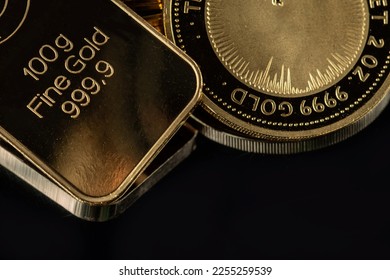 100 gram gold bar and a 2 troy ounce gold coin on a black  background.