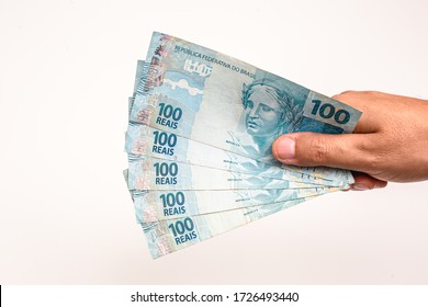 100 reais bills from Brazil, held by male hand on isolated white background. Banknotes of one hundred reais from brazil, payday. - Shutterstock ID 1726493440
