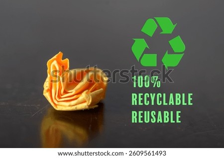 100% Recyclable and Reusable Concept Featuring Green Recycling Icon and Crumpled Orange Item