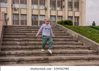 10.05.2019, Tula, Russia. A Little Boy Wearing Stripped Shirt Running Up And Down By Stairs. Kid Having Fun.