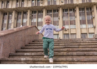 10.05.2019, Tula, Russia. A Little Boy Wearing Stripped Shirt Running Up And Down By Stairs. Kid Having Fun.