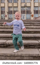 10.05.2019, Tula, Russia. A Little Boy Wearing Stripped Shirt Running Up And Down By Stairs. Kid Having Fun.