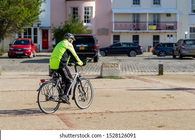 10/09/2019 Portsmouth, Hampshire, UK a middle aged man cycling wearing high visibility clothing and a cycle helmet