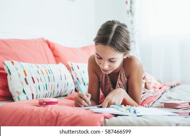 10-12 Years Old Pre Teen Girl Writing Diary In Pink Bedroom