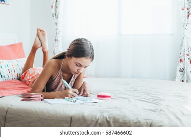 10-12 years old pre teen girl doing school homework in pink bedroom