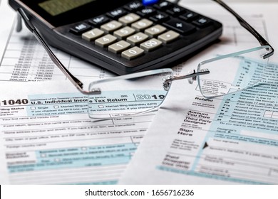 1040 Income Tax Return Form 2019 With Calculator And Focus Through Glasses. Concept Of Filing Taxes, Payment, Refund, And April 15, 2020 Tax Deadline