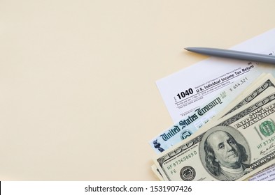 1040 Individual Income Tax Return Form With Refund Check And Hundred Dollar Bills On Beige Background