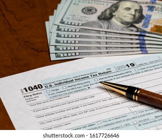 1040 Individual Income Tax Return Form 2019 With Ballpoint Pen And 100 Dollar Bills. Concept Of Filing Taxes, Payment, Refund, And April 15, 2020 Deadline Date