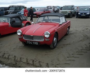 10th July 2021- A classic MG Midget, small two door convertible sports car, parked on the sandy  beach at Pendine, Carmarthenshire, Wales, UK.