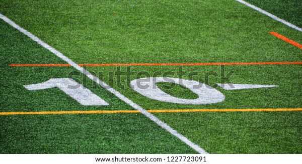 The 10-yard-line of an american football field with\
artificial turf