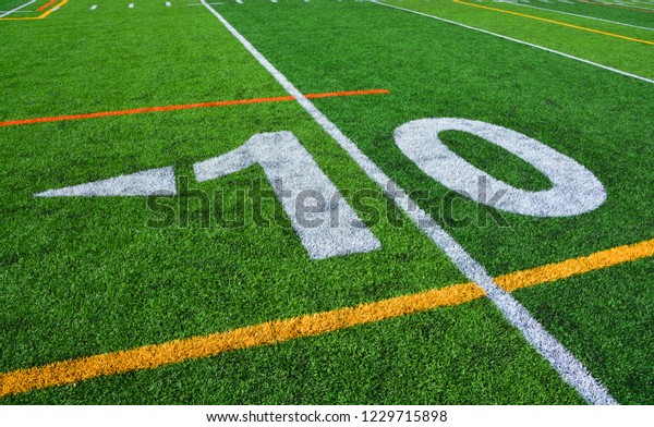The 10-yard-line of an american football field with\
artificial turf