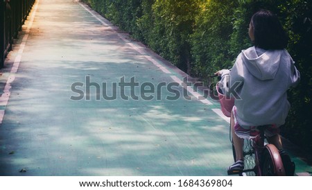 A 10-year-old Asian girl riding a bicycle in the garden Joyfully There is a high determination to reach the goal on the finish line. In the afternoon of a tropical town