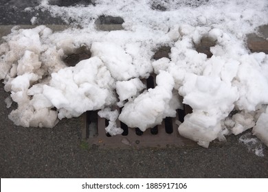 11 - Close Up Of A Kerbside Storm Drain Nearly Blocked By Snow. Urban Water Management Problem As The Melting Snow Can Cause Flooding.