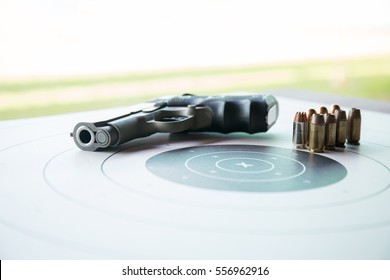 11 mm or .45 bullets on  bullseye target with blurred pistol gun and copy space