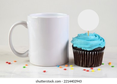 11 ounce coffee mug resting next to a tempting blue frosted chocolate cupcake.  - Shutterstock ID 2214402943