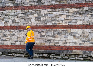 11/05/2019 Portsmouth, Hampshire, UK A Builder Or Construction Worker Wearing High Visibility Clothing And A Hard Hat Walking