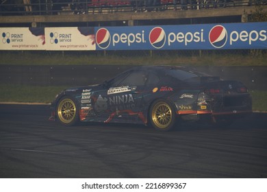 11-05-2022 Riga, Latvia A Black Car With Gold Rims Driving On A Track, A Car That Has Been Turned Into A Burn Racing.