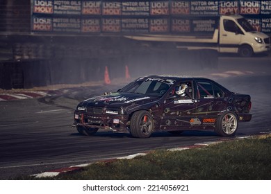 11-05-2022 Riga, Latvia A Car Driving On A Track With Smoke Coming Out Of It, The Car Is Taking On Another Race At Night.