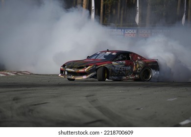 11-05-2022 Riga, Latvia A Car With A Lot Of Smoke Coming Out Of It, A Person Driving On A Track And Pulling Something Out Of The Smoke.