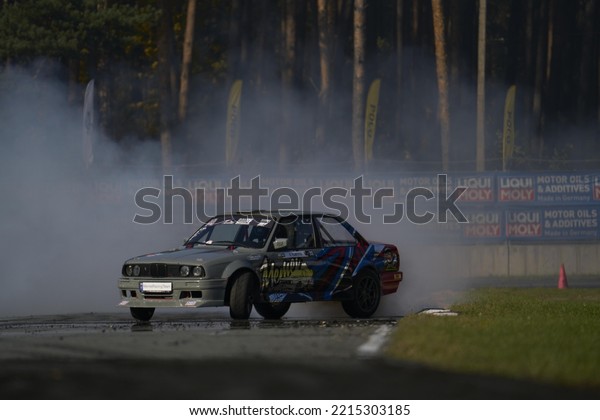 11-05-2022 Riga, Latvia a car with smoke coming\
out of it driving on a track, a smoke filled car drifts in smoke on\
the track.