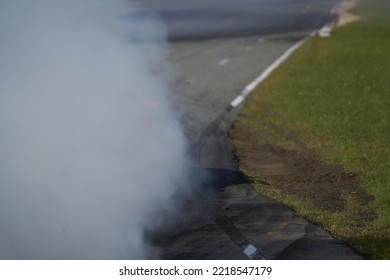 11-05-2022 Riga, Latvia A Person On A Motorcycle With Smoke Coming Out Of It, Smoke Is Coming Out From Under A Tire Track.