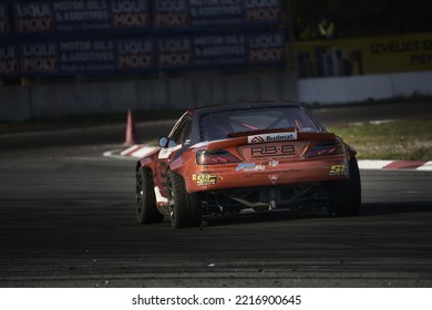 11-05-2022 Riga, Latvia A Red Car Driving Down A Race Track, There Is A Car Driving On The Track With No Wheels.