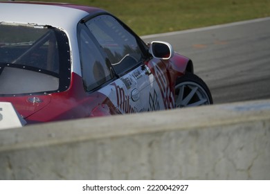 11-05-2022 Riga, Latvia A Red And White Car Driving On A Race Track, The Back End Of A Sports Car In Motion.