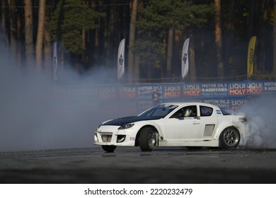 11-05-2022 Riga, Latvia A White Car With A Lot Of Smoke Coming Out Of It, A Sports Car Drags A Smoke Trail During A Race.