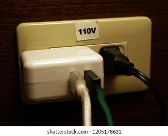 110v socket fully plugged by various plugs. AC power plugs and sockets. A dangerous usage of fully plugged socket.