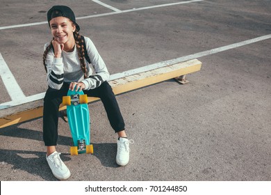 11-12 years old tween girl wearing fashion sportswear rollerskating on skateboard in the city street, urban hipster style
