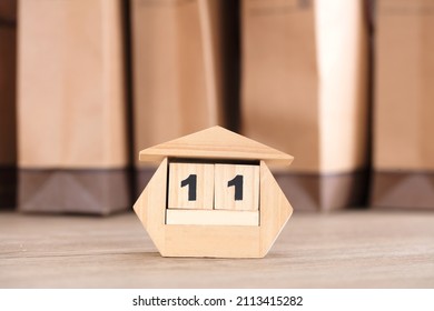 The 11th Is Displayed On A Small Wooden Desk Calendar In Front Of The Shopping Bag