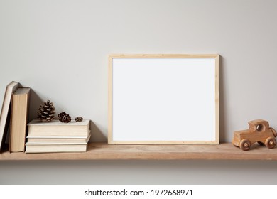 11x14 thin wood horizontal frame mockup for art and quotes, sitting on a wooden shelf. Vintage stack of books, old toy car and pine cones as props. - Powered by Shutterstock