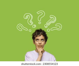 An 11-year-old boy, touching his chin with a dubious expression and looking up as if thinking, isolated on a green background with graphic question marks around him - Powered by Shutterstock