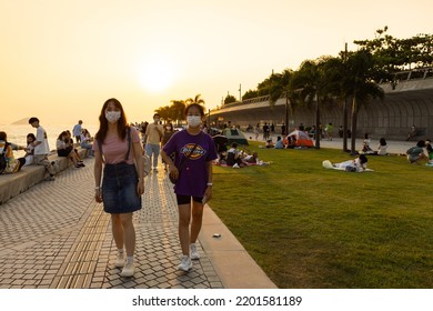 12 9 2022 Youngsters Students Boy And Girl Chat And Walk During Sunset In West Kowloon Waterfront Promenade, Hong Kong In Evening. Back Light Shot