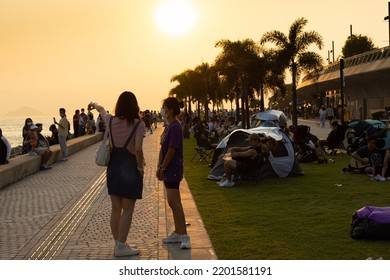 12 9 2022 Youngsters Students Boy And Girl Chat And Walk During Sunset In West Kowloon Waterfront Promenade, Hong Kong In Evening. Back Light Shot