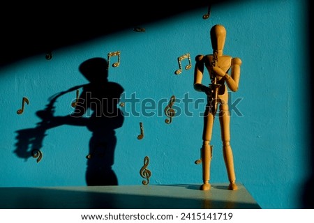 A 12 inch wooden drawing mannequin figure plays a saxophone against a blue backdrop with gold musical notes and treble and bass clefs