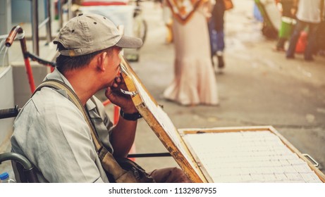 12 July 2018 , Chatuchak Market In Bangkok , Old Asian Man With Disabilities Disabled A Person With Differently Abled Sitting In A Wheelchair Waiting Customer To Buy Thai Lottery Ticket .