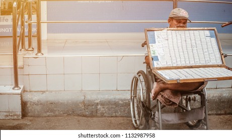 12 July 2018 , Chatuchak Market In Bangkok , Old Asian Man With Disabilities Disabled A Person With Differently Abled Sitting In A Wheelchair Waiting Customer To Buy Thai Lottery Ticket .