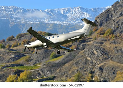 A 12 seater passenger aircraft comes in to land in the mountains. Pilatus PC-12 NG