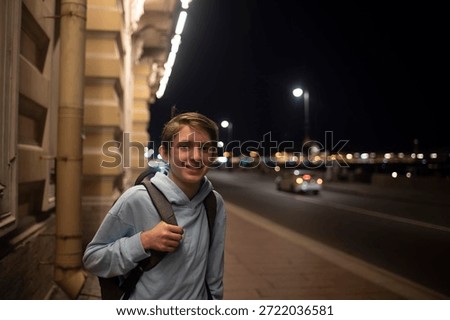 A 12 year old boy with a backpack walks along the street along the road in the evening.