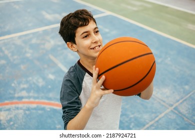 12 Year Old Boy Playing Basketball. Teenager Training Basketball Outdoors.